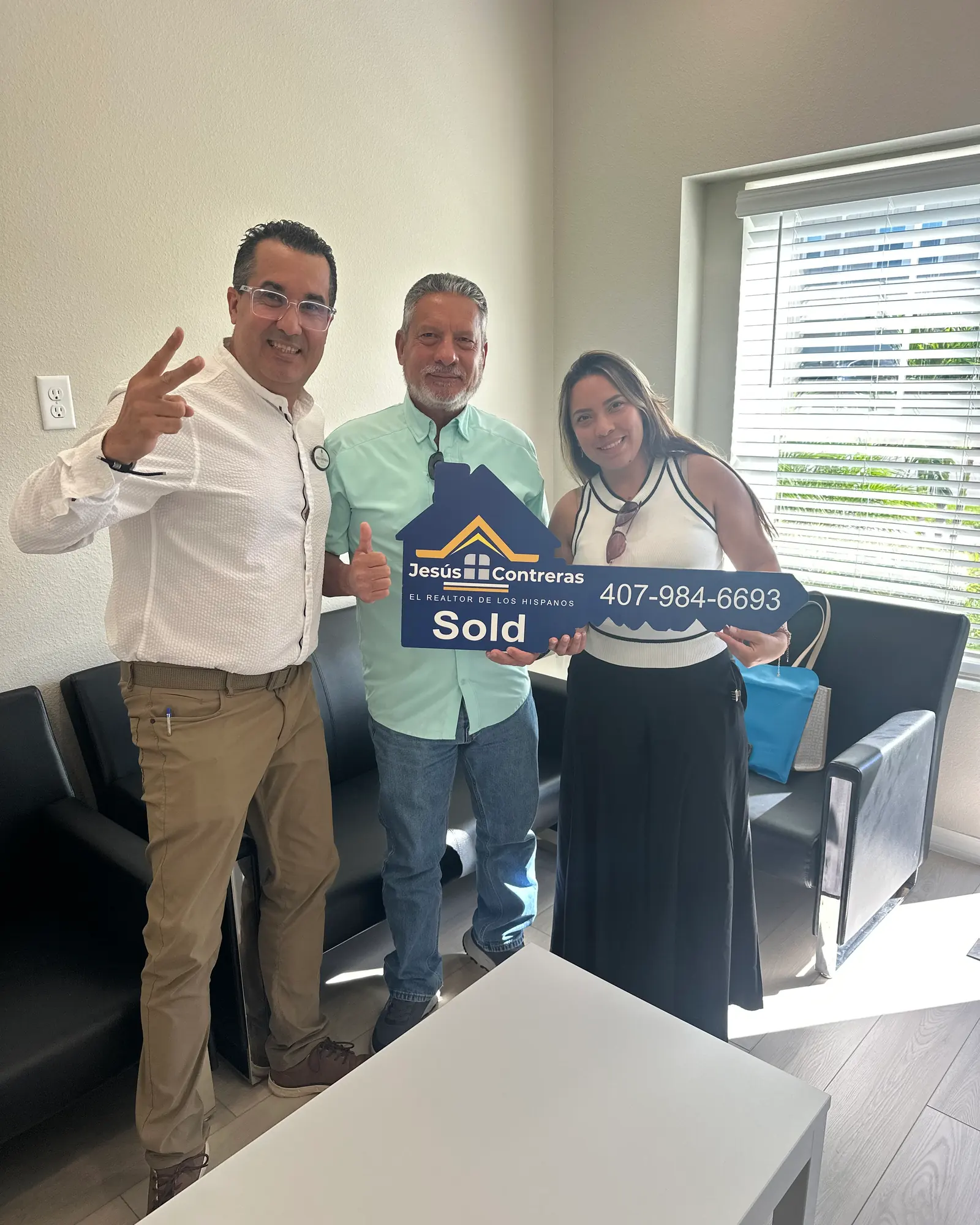 Jesús Contreras con dos clientes que sostienen el letrero de vendido