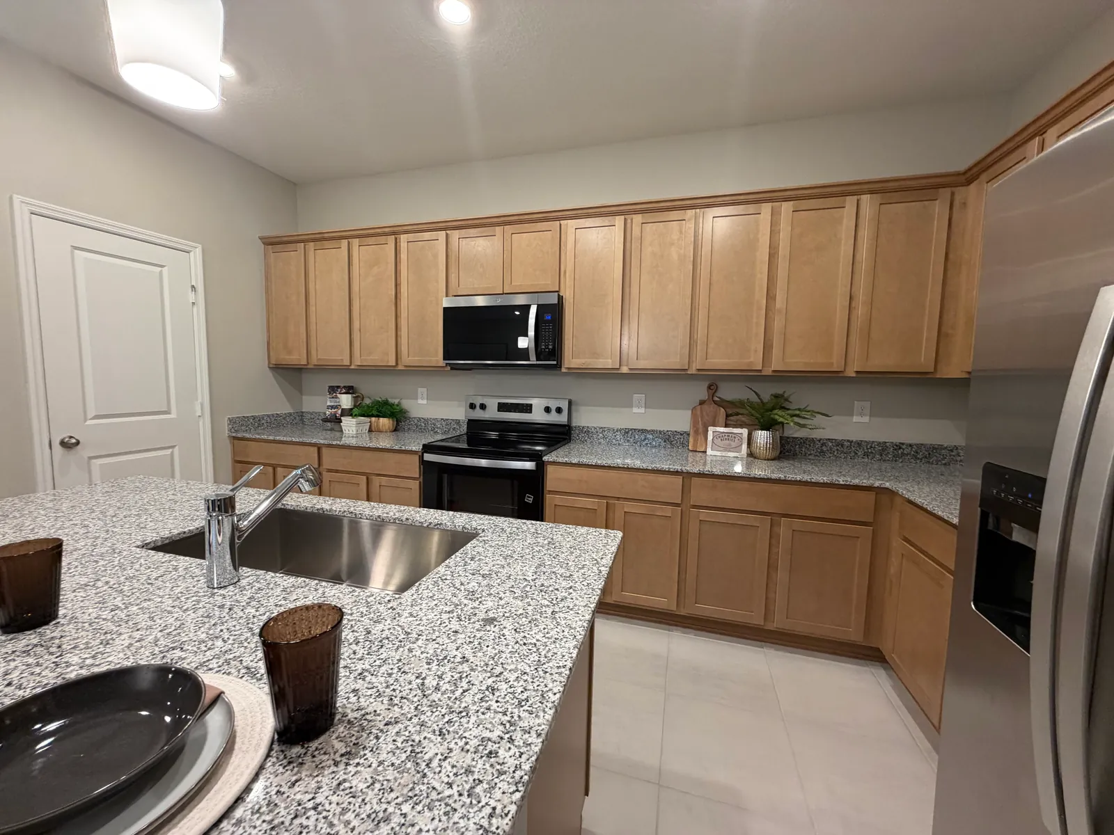 Cocina con gabinetes de madera, isla de granito y electrodomésticos de acero