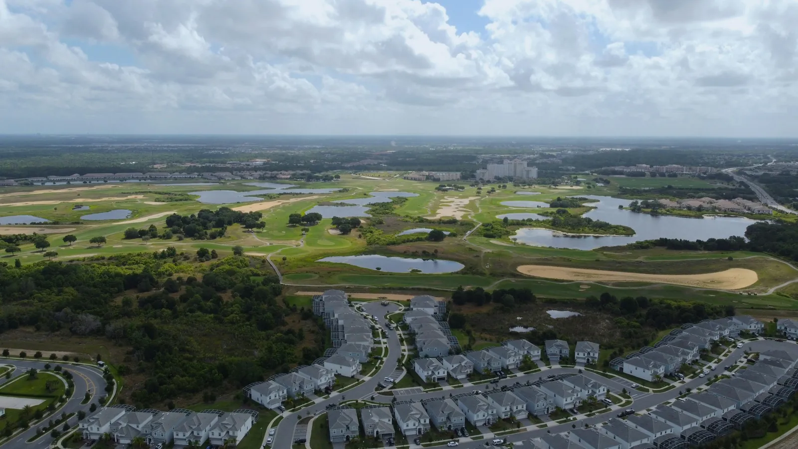 Vista aérea de un campo de golf con lagunas junto a una comunidad residencial