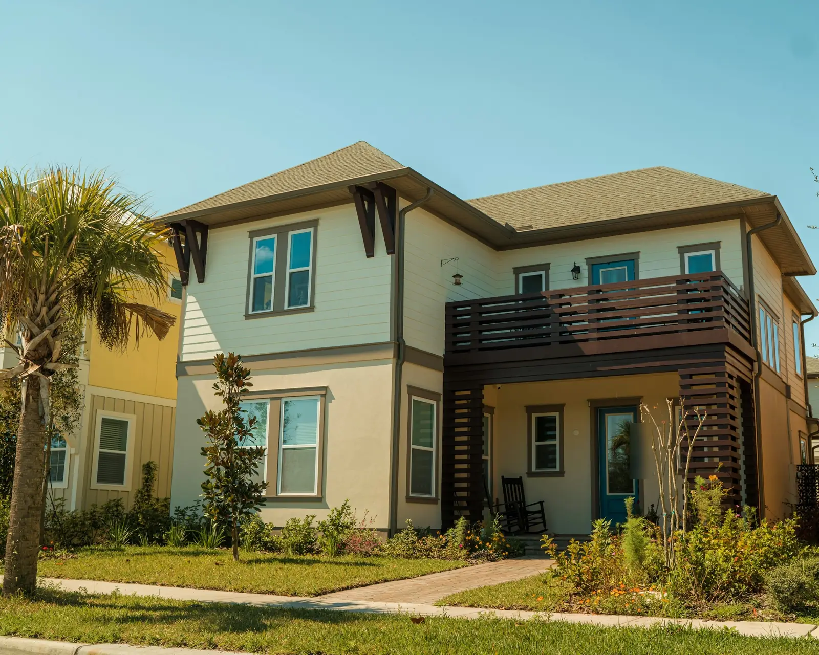 Casa de dos plantas con balcón de madera y una palmera, en Lake Nona